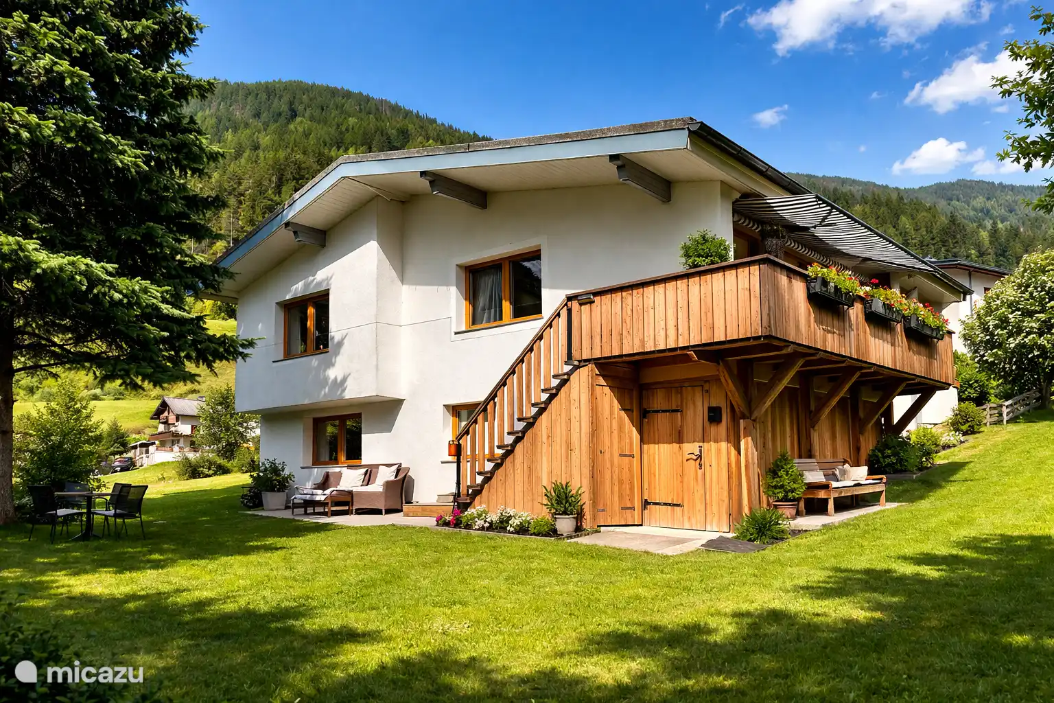 Parte trasera de la casa con entrada extra al balcón. Amplio césped soleado para tomar el sol