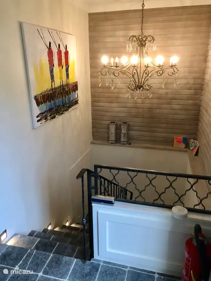 Hall con escaleras de piedra a dormitorios y baños.