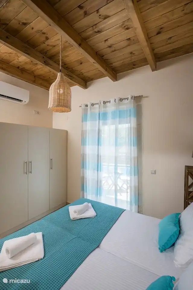 Downstairs bedroom with air conditioning and again the beautiful wooden ceiling, door to the swimming pool and large wardrobes with clothes hangers.