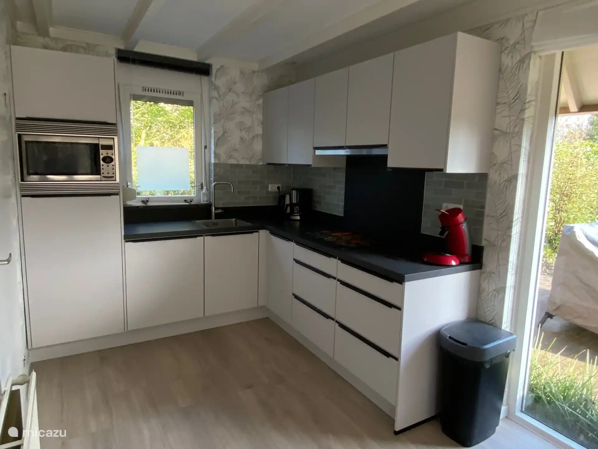 Die offene Küche ist funktional eingerichtet und verfügt über eine Kombimikrowelle, ein Cerankochfeld, eine Kaffeemaschine und einen Wasserkocher, ein Toasterbügeleisen und einen Toaster. Im Hauswirtschaftsraum gibt es einen Geschirrspüler, eine Waschmaschine und einen Trockner.