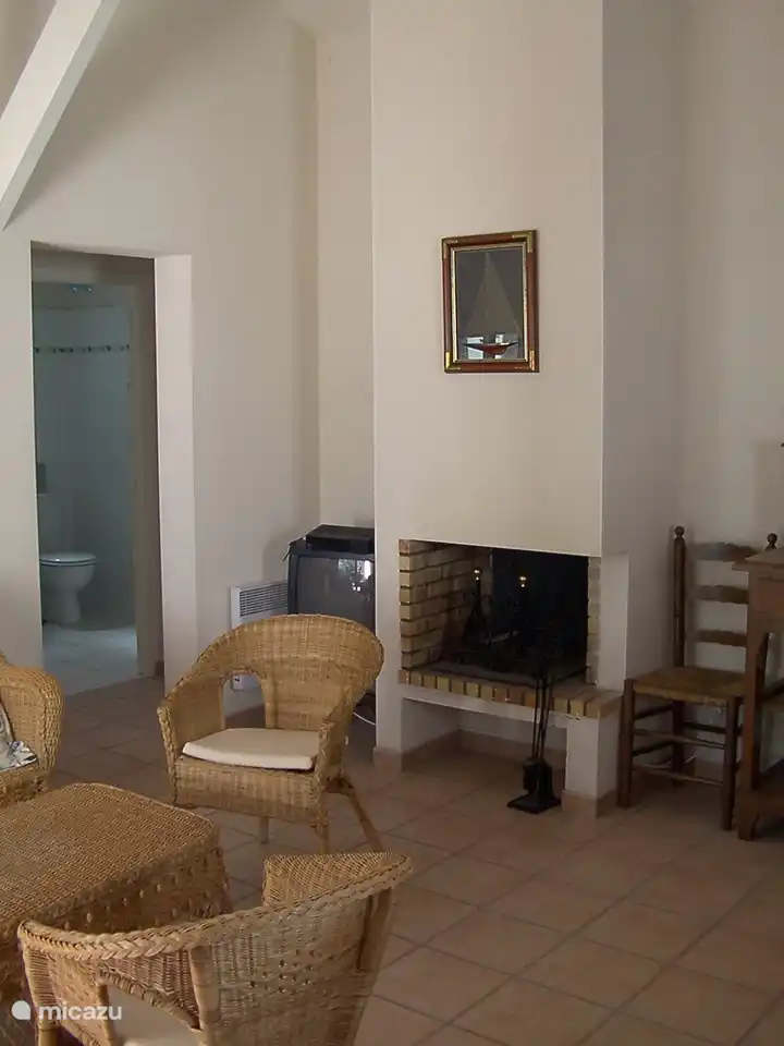 .Uitzicht vanuit de keuken naar het zitgedeelte. De doorgang naast de open haard leidt naar de badkamer en slaapkamers.