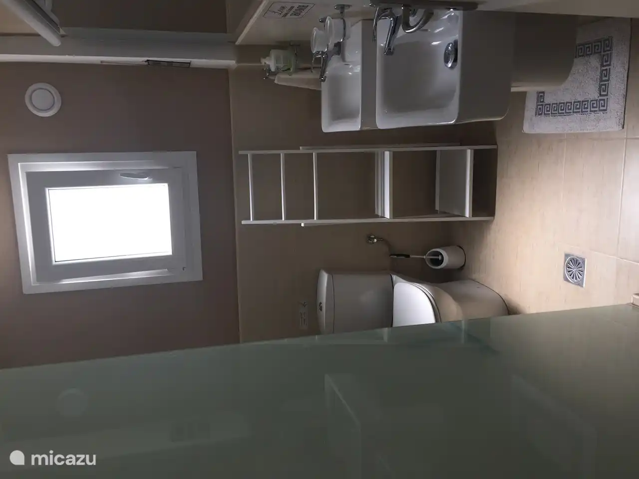 Bathroom has walk-in shower with frosted glass wall.