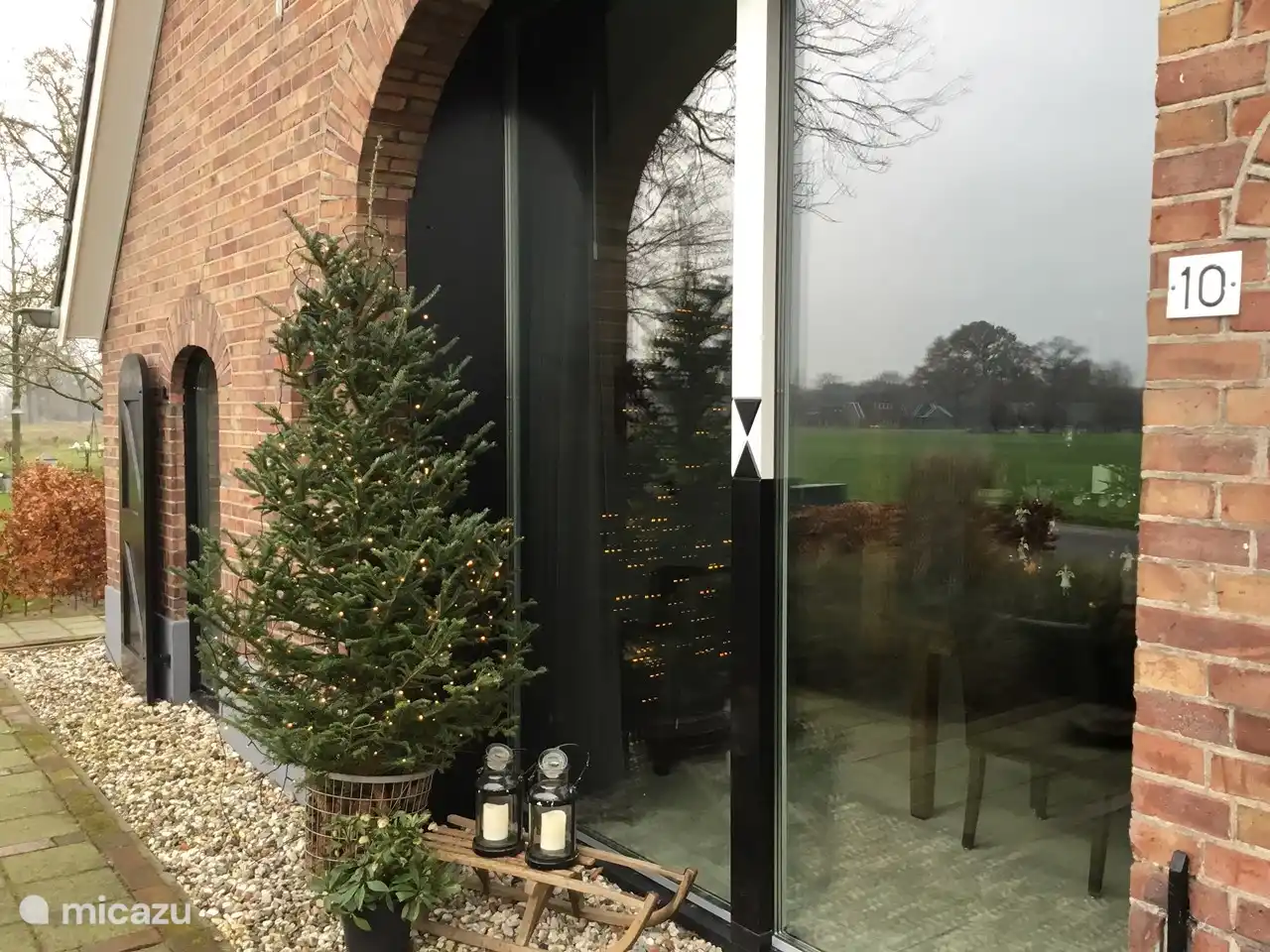 Ein gemütlicher Weihnachtsbaum mit Lichtern vor dem Fenster.