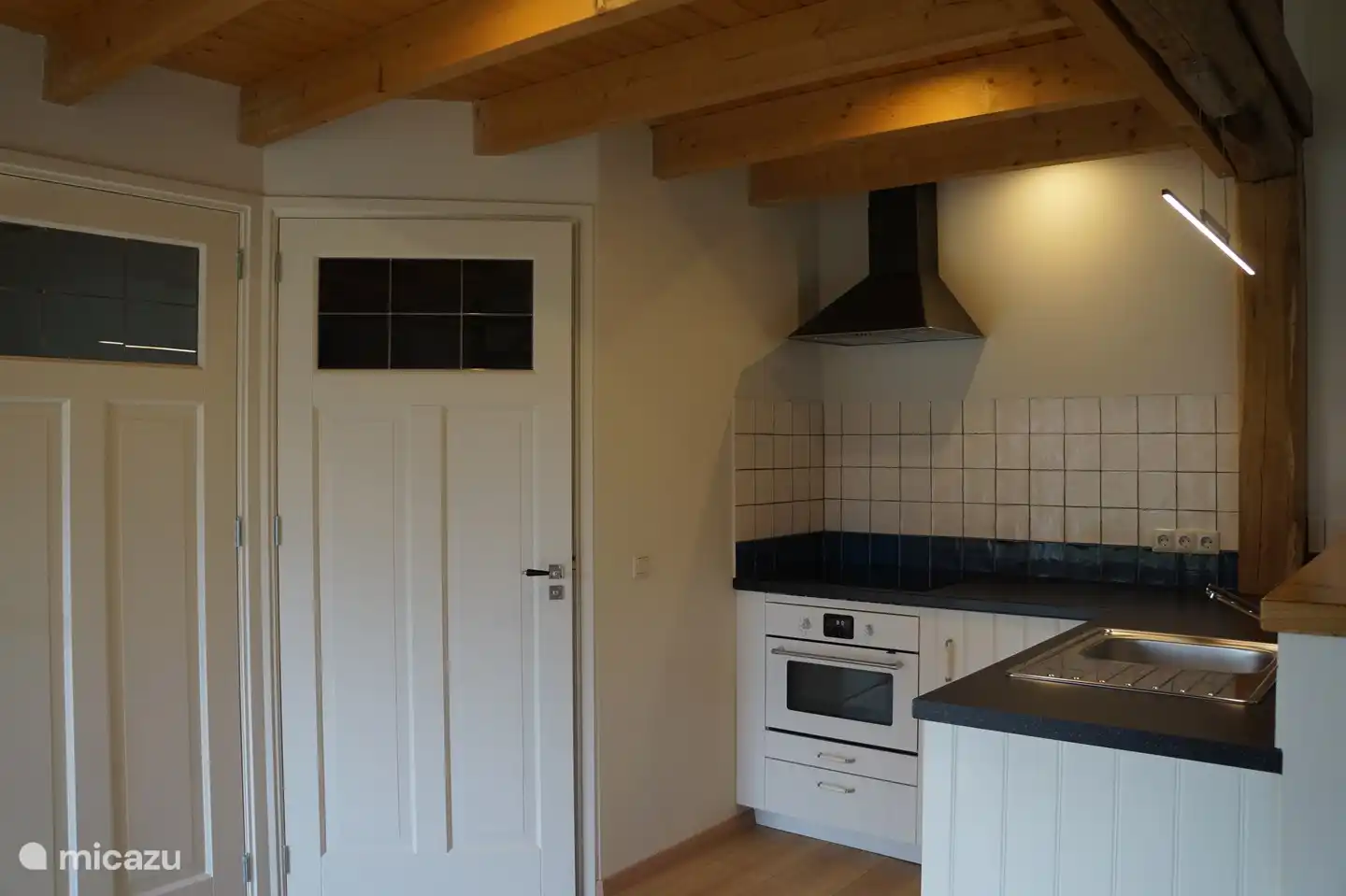 Küche mit Induktionsherd, Backofen, Mikrowelle, Kühlschrank und Geschirrspüler.