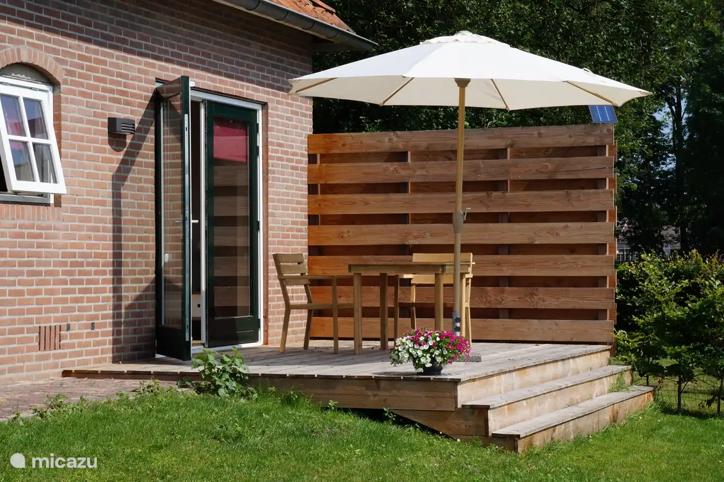 Private Terrasse mit Tisch, Stühlen und Sonnenschirm.