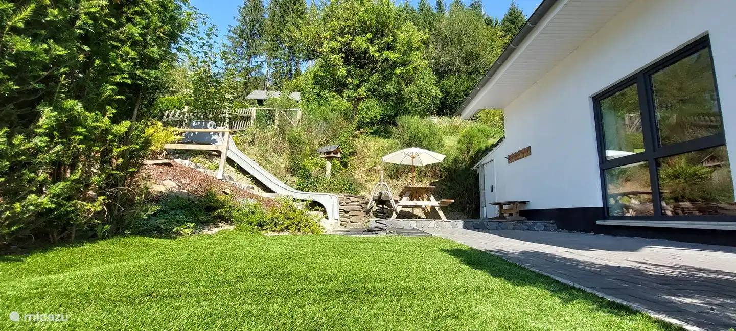 Lado de la casa con parque infantil y gran terraza.