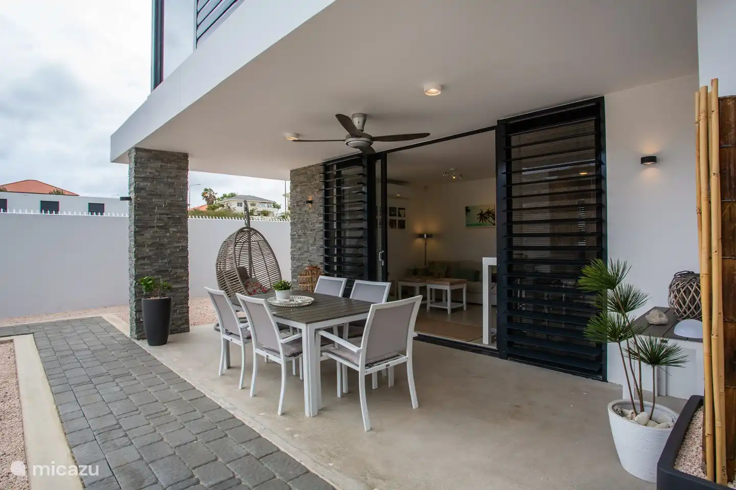 Die großzügige überdachte Terrasse bietet einen Esstisch und einen bequemen Relaxsessel zum Entspannen. Darüber hinaus sorgt ein Ventilator für eine angenehme Brise und zusätzlichen Komfort.