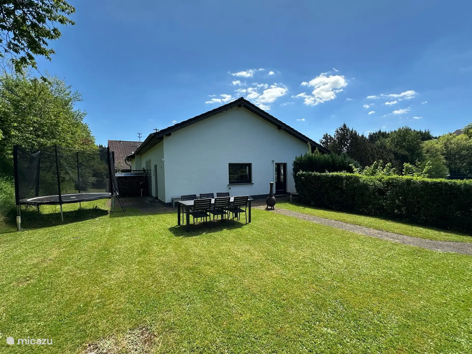Tuin op de woonverdieping met grote eettafel en trampoline