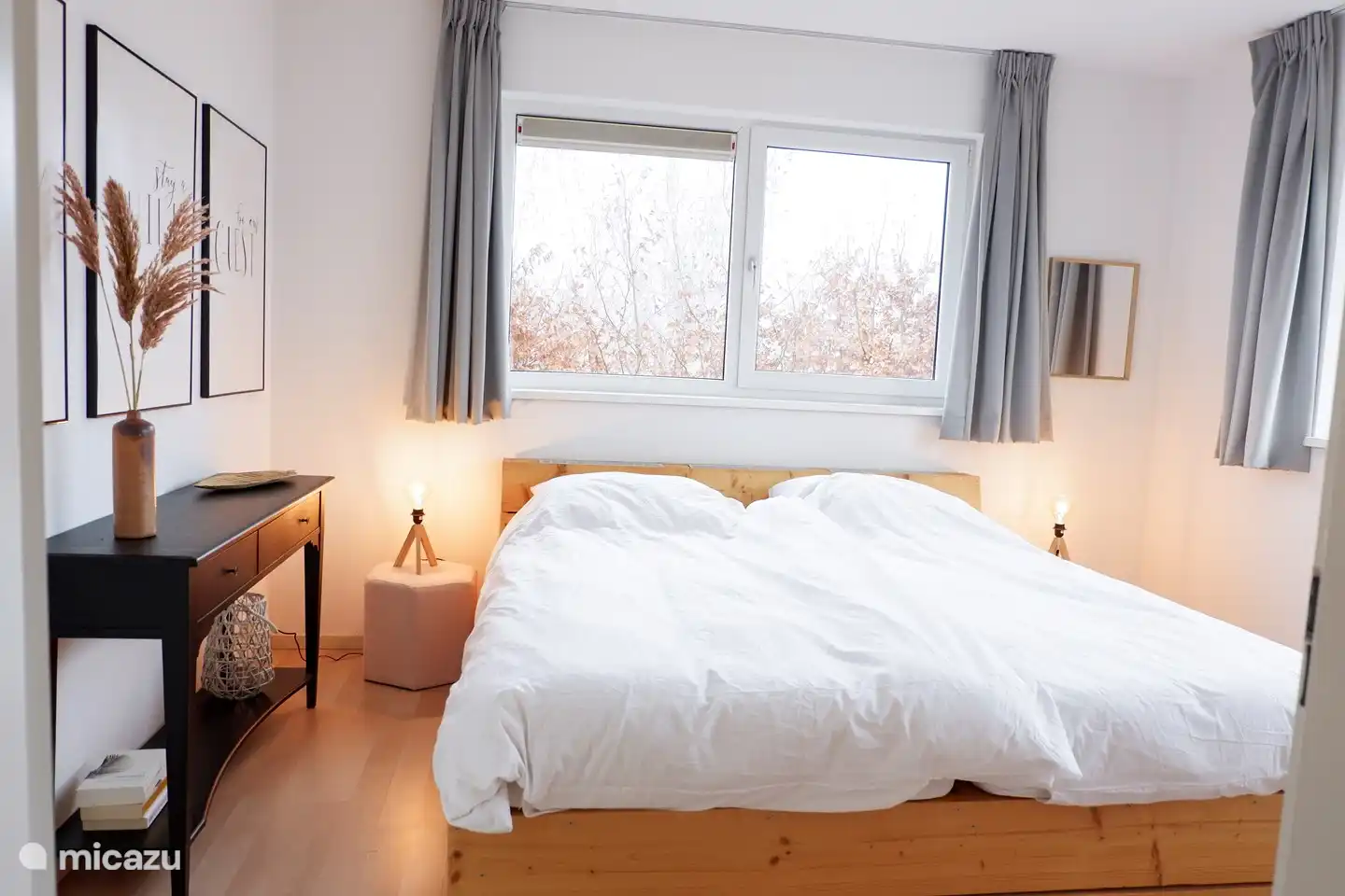 Dieses Holzbett ist schön groß und die sanften Farben machen dieses Zimmer schön und gemütlich.