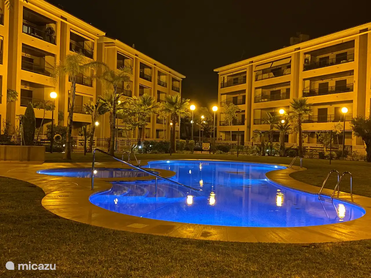 Der Gemeinschaftsgarten mit Swimmingpool ist nachts beleuchtet