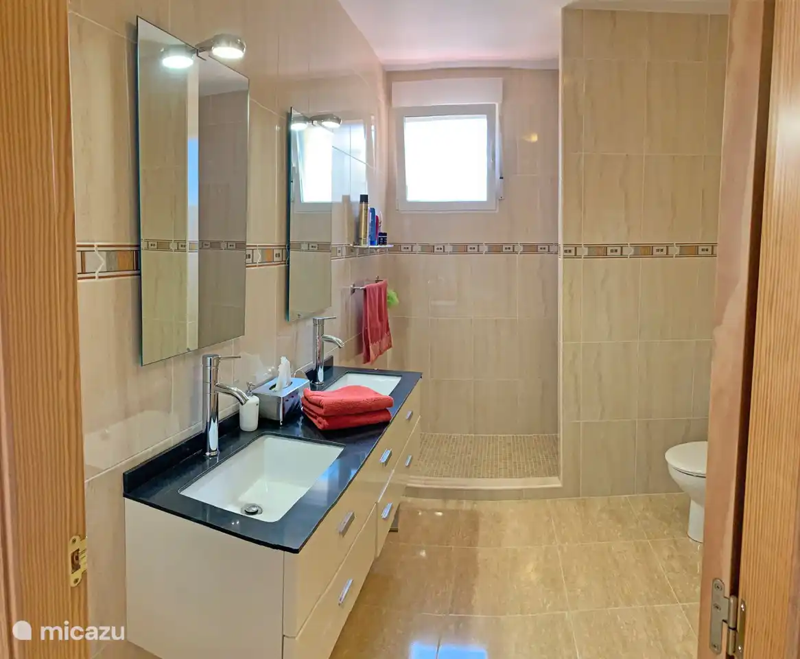 Das Badezimmer verfügt über ein Doppelwaschbecken, eine ebenerdige Dusche und eine Toilette. Hier befinden sich auch die Waschmaschine und der Trockner.