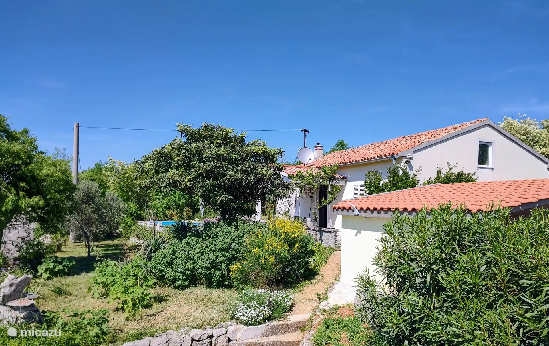 Maison authentique avec vue mer dans un environnement verdoyant.