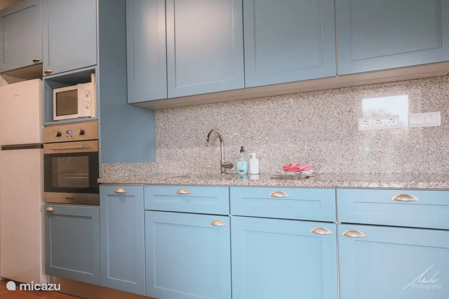 Keuken met koelkast, vriezer, microgolfoven, oven.