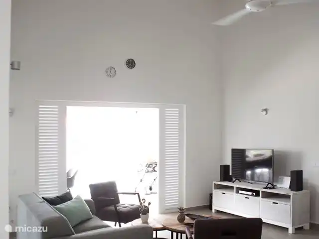 Bunita Blenchi huren in Curaçao, Banda Abou (west), Fontein - villa De woonkamer is voorzien van een zitbank en 2 relax stoelen. Daarnaast uiteraard een tv meubel met tv en home cinema dvd set. U kunt muziek luisteren via de 2 Sonos boxen. Voor de verdere inrichting is er een dressoir en boekenkast. De plafond ventilator zorgt voor de verkoeling