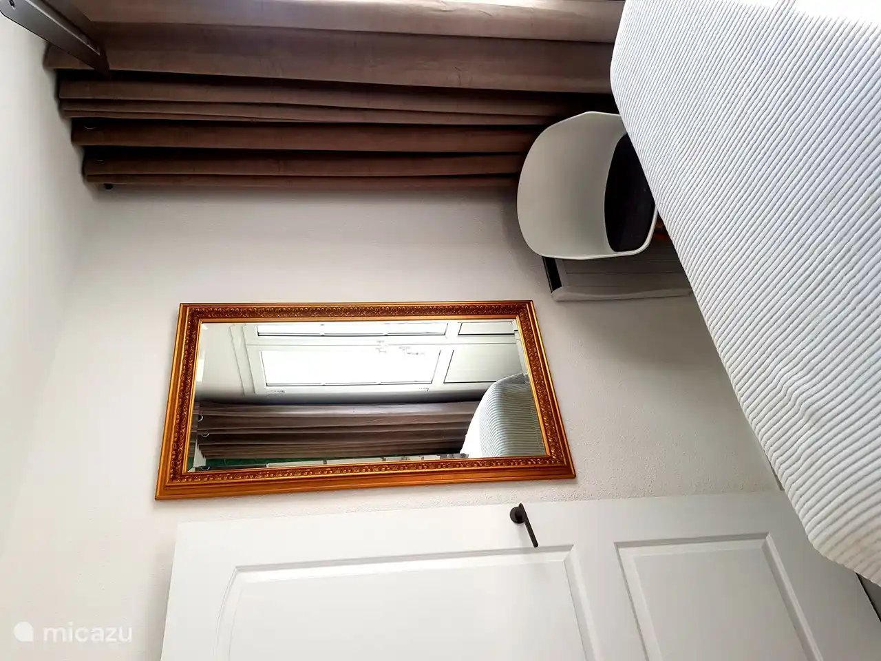 Bonito espejo con silla frente a la cama.