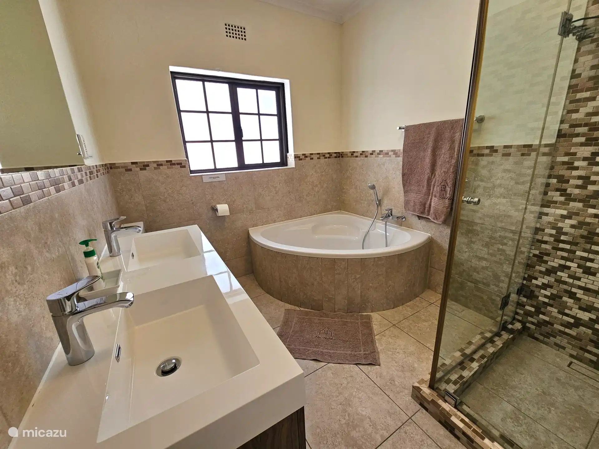 Badkamer op begane grond met hoekbad en douche, douche cabine, dubbele wastafel en toilet