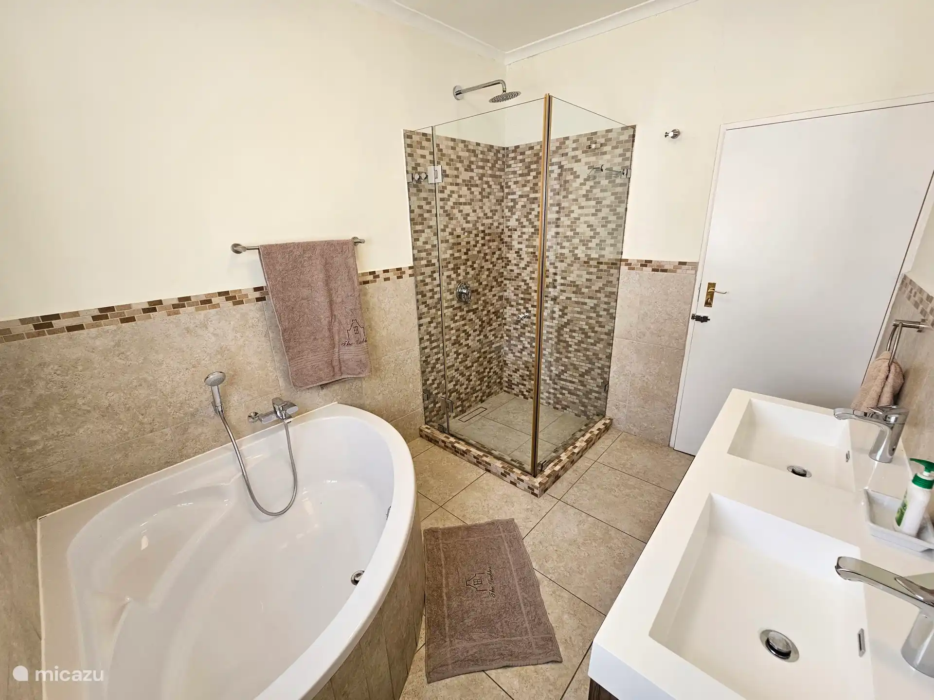 Badkamer op begane grond met hoekbad en douche, douche cabine, dubbele wastafel en toilet