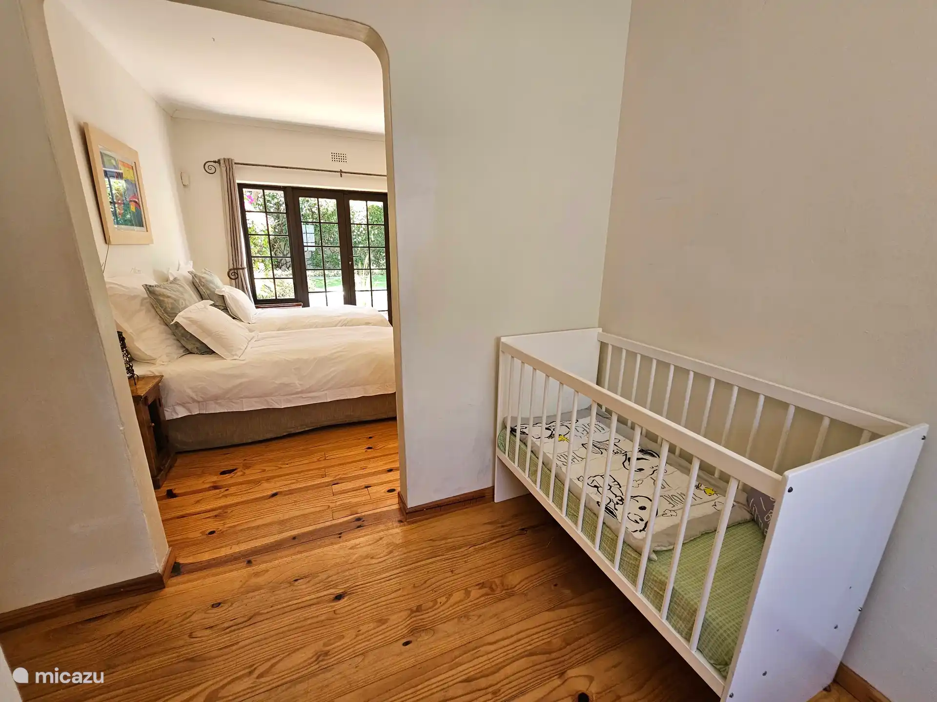 Slaapkamer met twee single bedden, op de begane grond en een naastgelegen ruimte met buro en kinderbedje