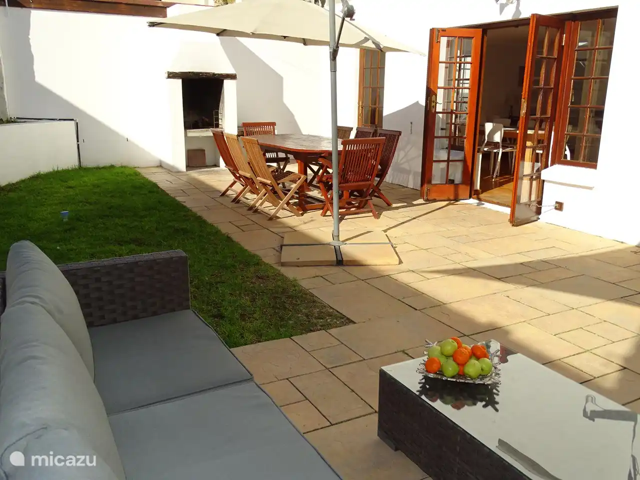 Joli jardin clos avec barbecue (braai), grande table à manger, parasol, salon de jardin et ombrière.