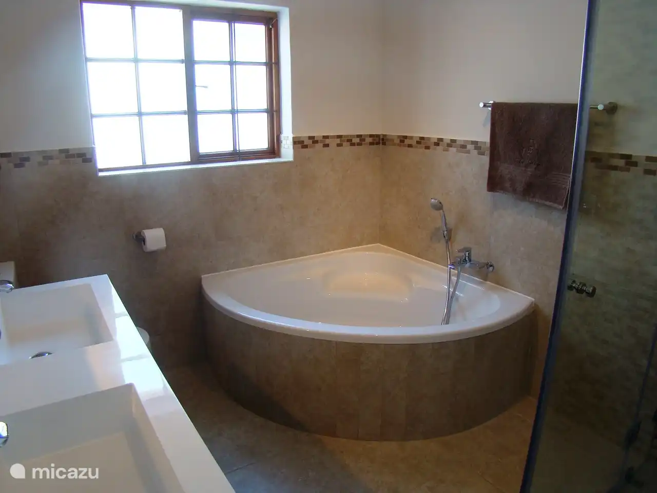 Salle de bain au rez-de-chaussée avec douche à l'italienne, baignoire, double vasque et toilettes.