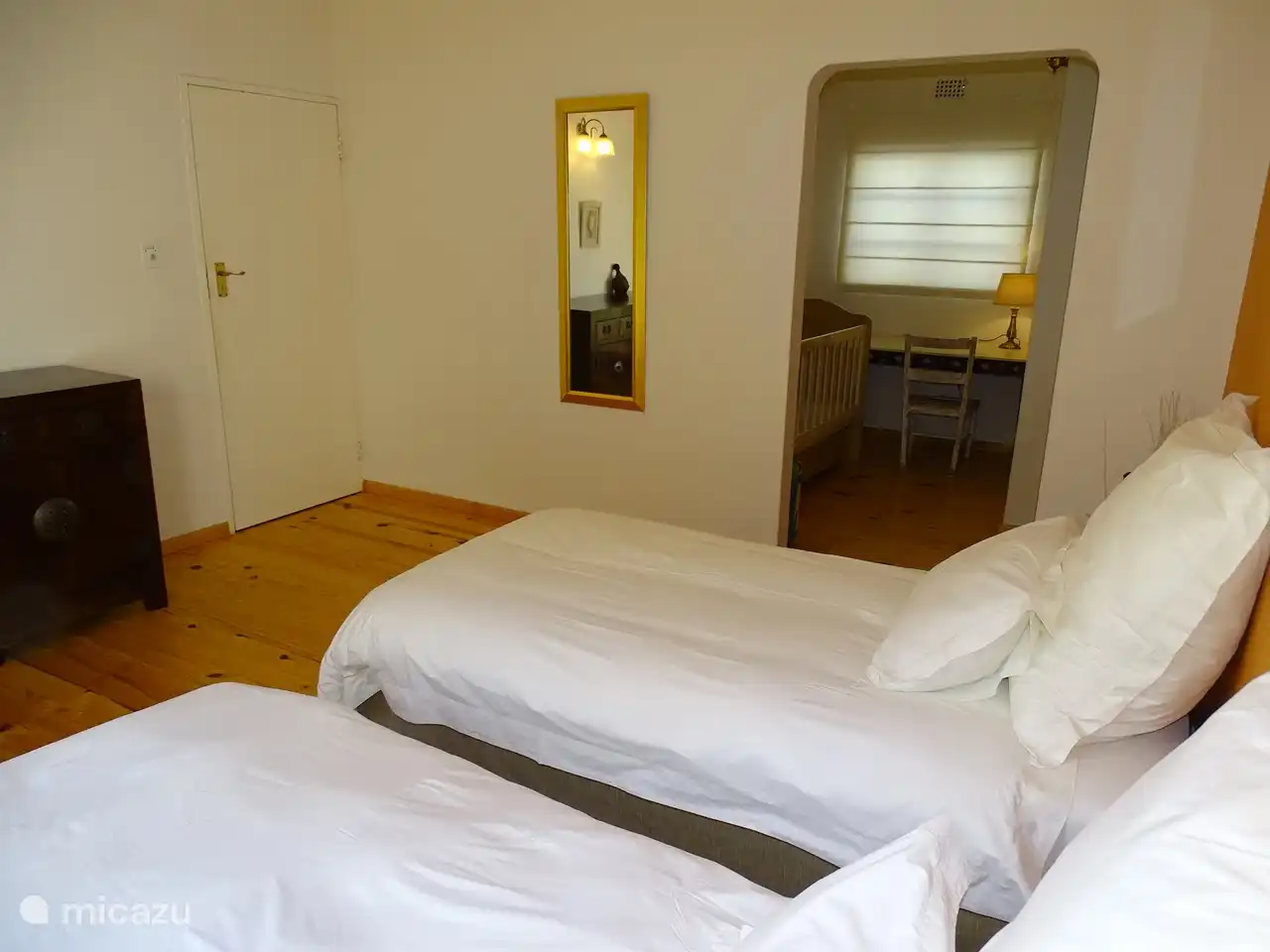 Chambre avec deux lits simples et portes-fenêtres donnant sur le jardin, également dans cette chambre un lit (bébé) et un bureau.