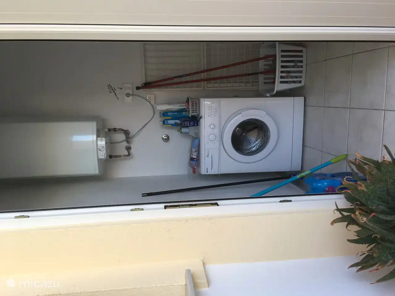 De wasmachine staat buiten het appartement in een ruime kast waar ook de reserve tuinstoelen staan die je mee kan nemen naar de zee of naar het zwembad om daar te genieten van de rust