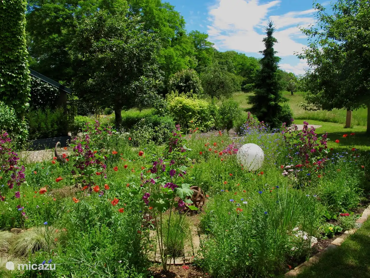 The gite is located to the left of the large garden