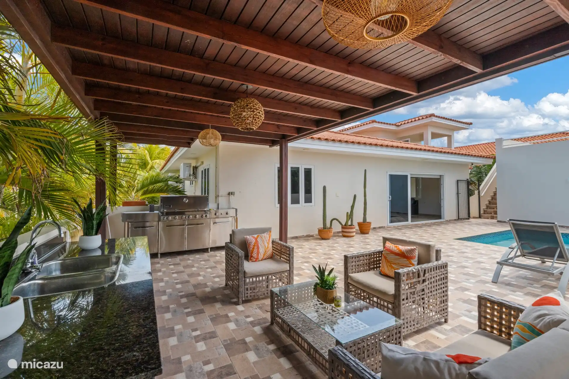 Une terrasse couverte avec salle à manger et cuisine extérieure — idéale pour les repas en plein air.