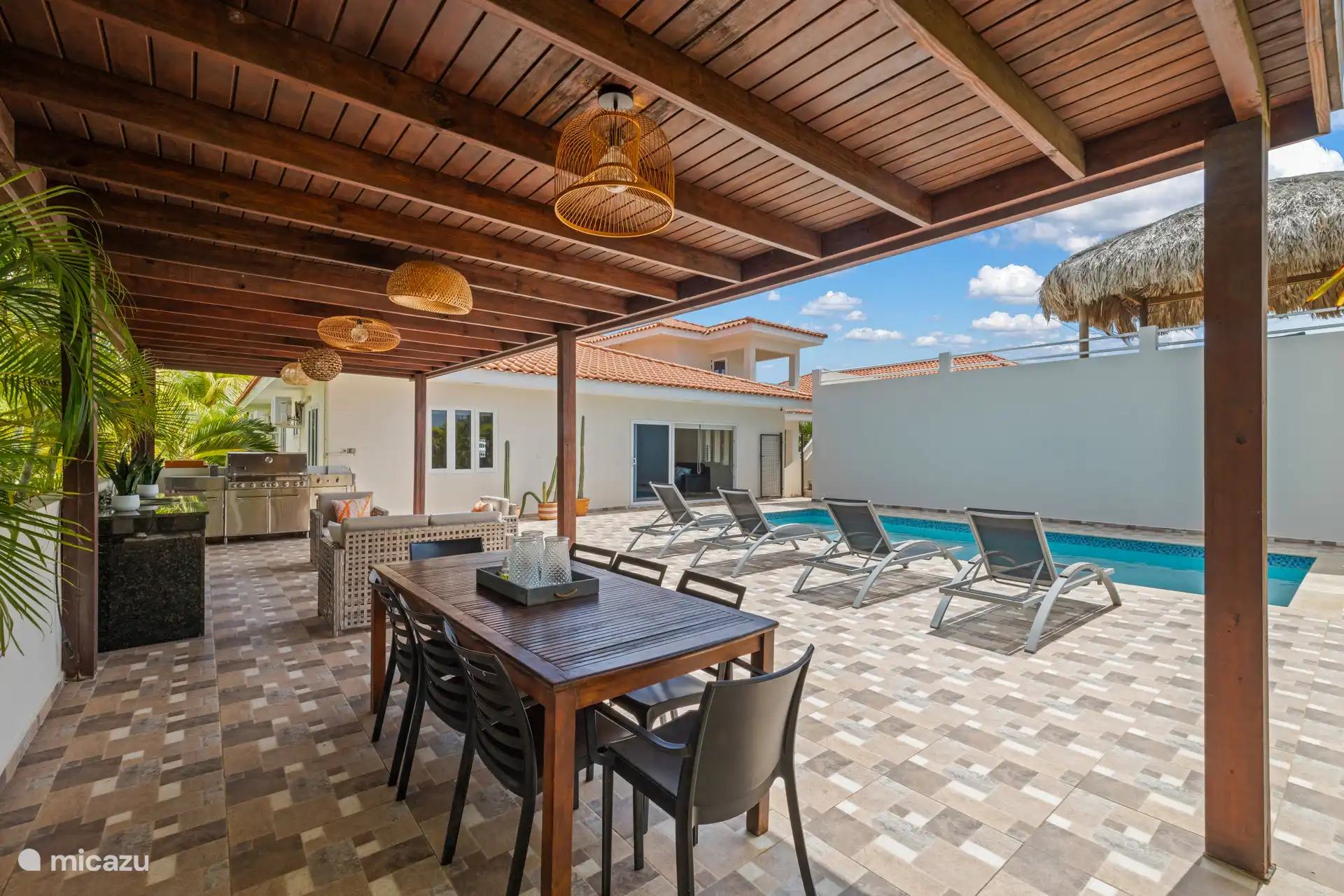 Une terrasse couverte avec salle à manger et cuisine extérieure — idéale pour les repas en plein air.