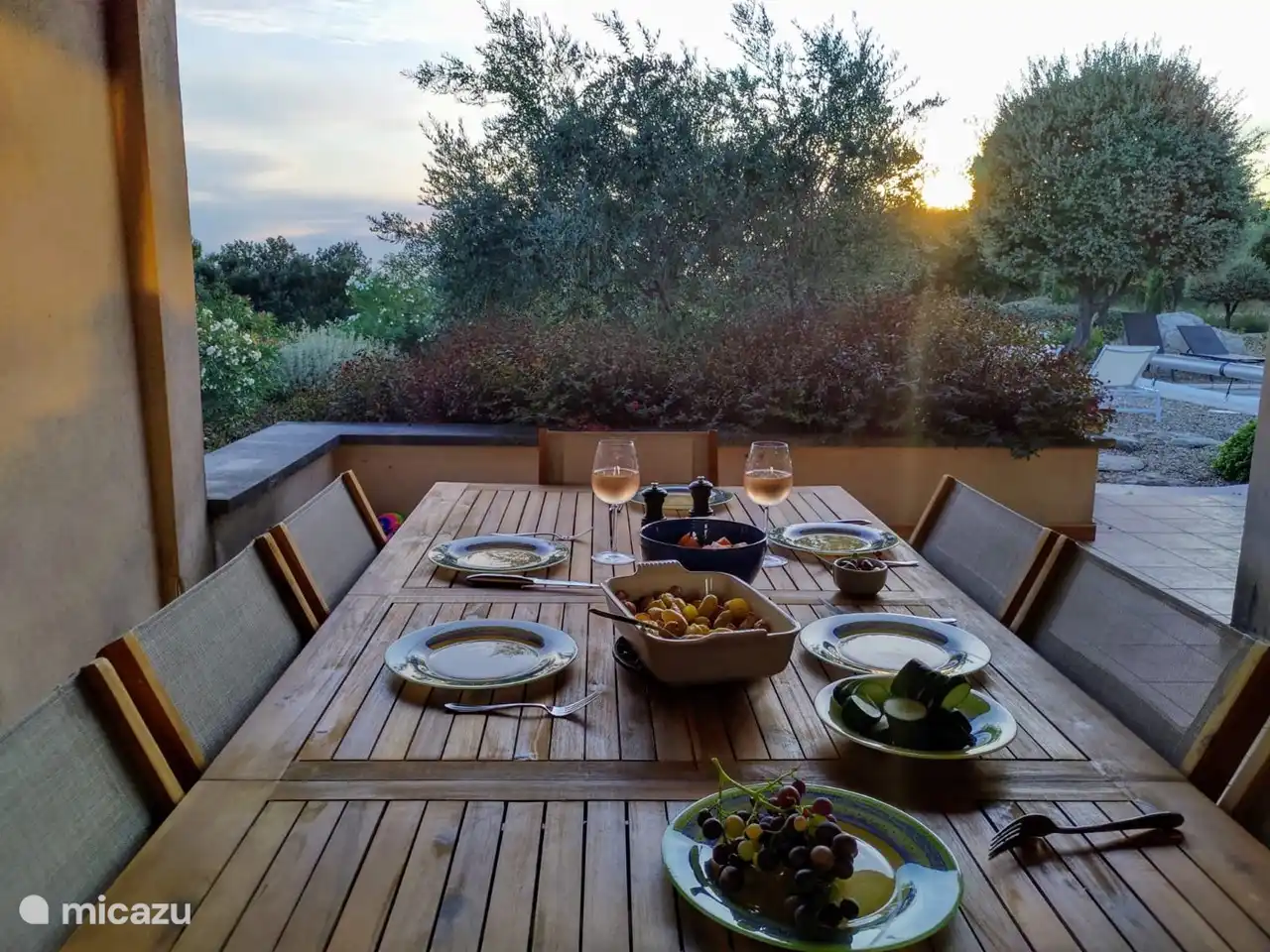 überdachter Esstisch neben der Küche mit Blick auf den dahinter liegenden Garten.