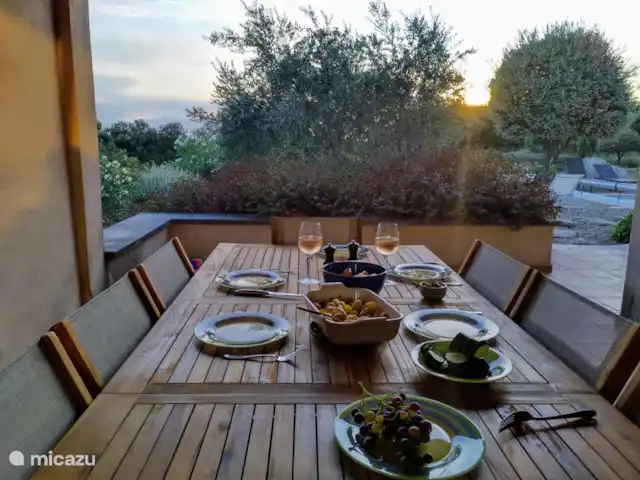 Location de Vacances France, Vaucluse, Saumane-de-Vaucluse, villa - Villa113 Domaine les Demeures du Luc table à manger couverte adjacente à la cuisine avec vue sur le jardin derrière.
