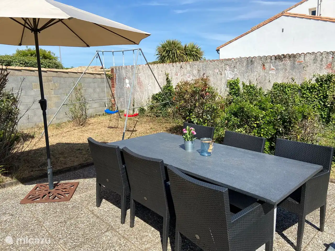 Jardin avec 2 balançoires, salon de jardin et un grand parasol flottant