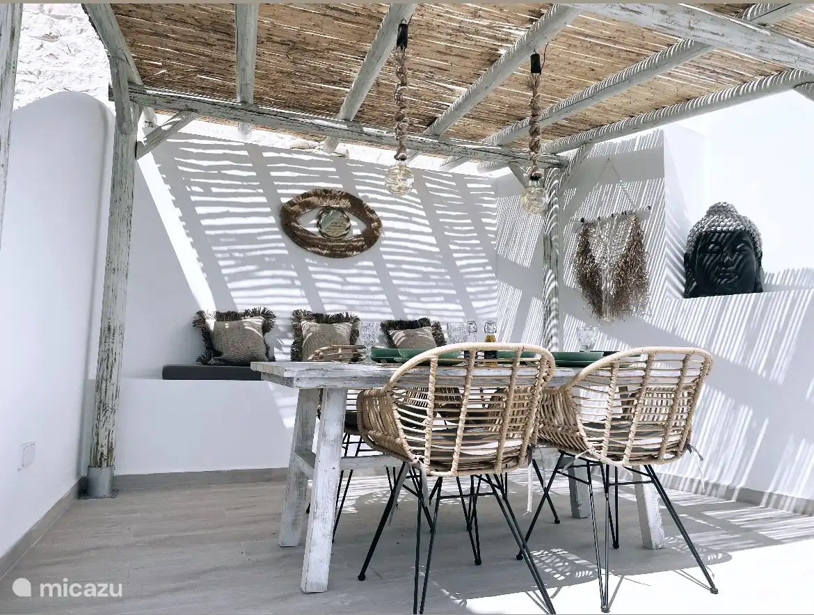 Draußen mehrere Terrassen im Boho-Stil! Terrasse mit Esstisch und 4 Stühlen unter großer strohgedeckter Pergola mit vollem Meerblick