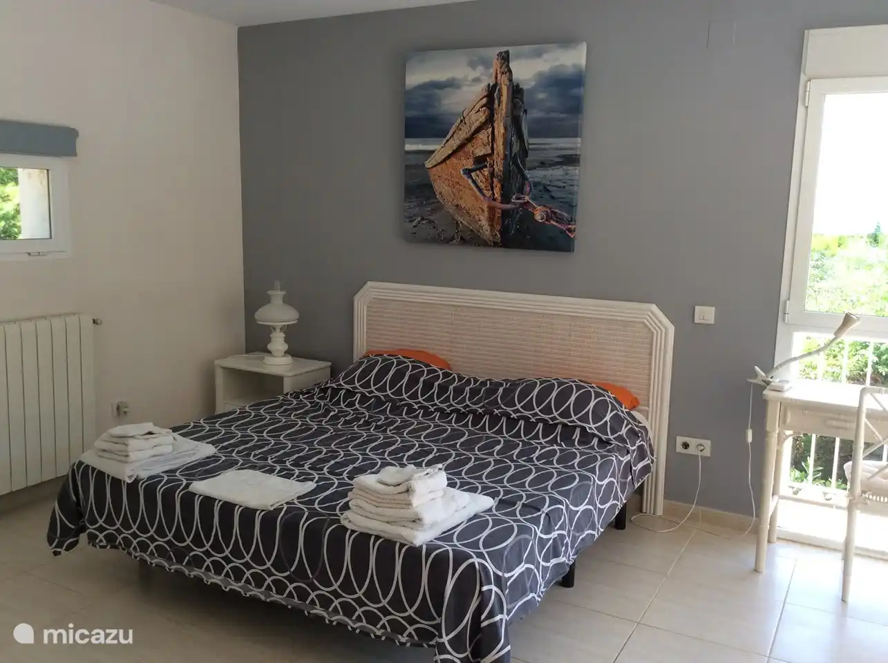 Großes graues Zimmer mit eigenem Bad, Meerblick und mit Schiebefenster zur Terrasse mit Lounge-Set.