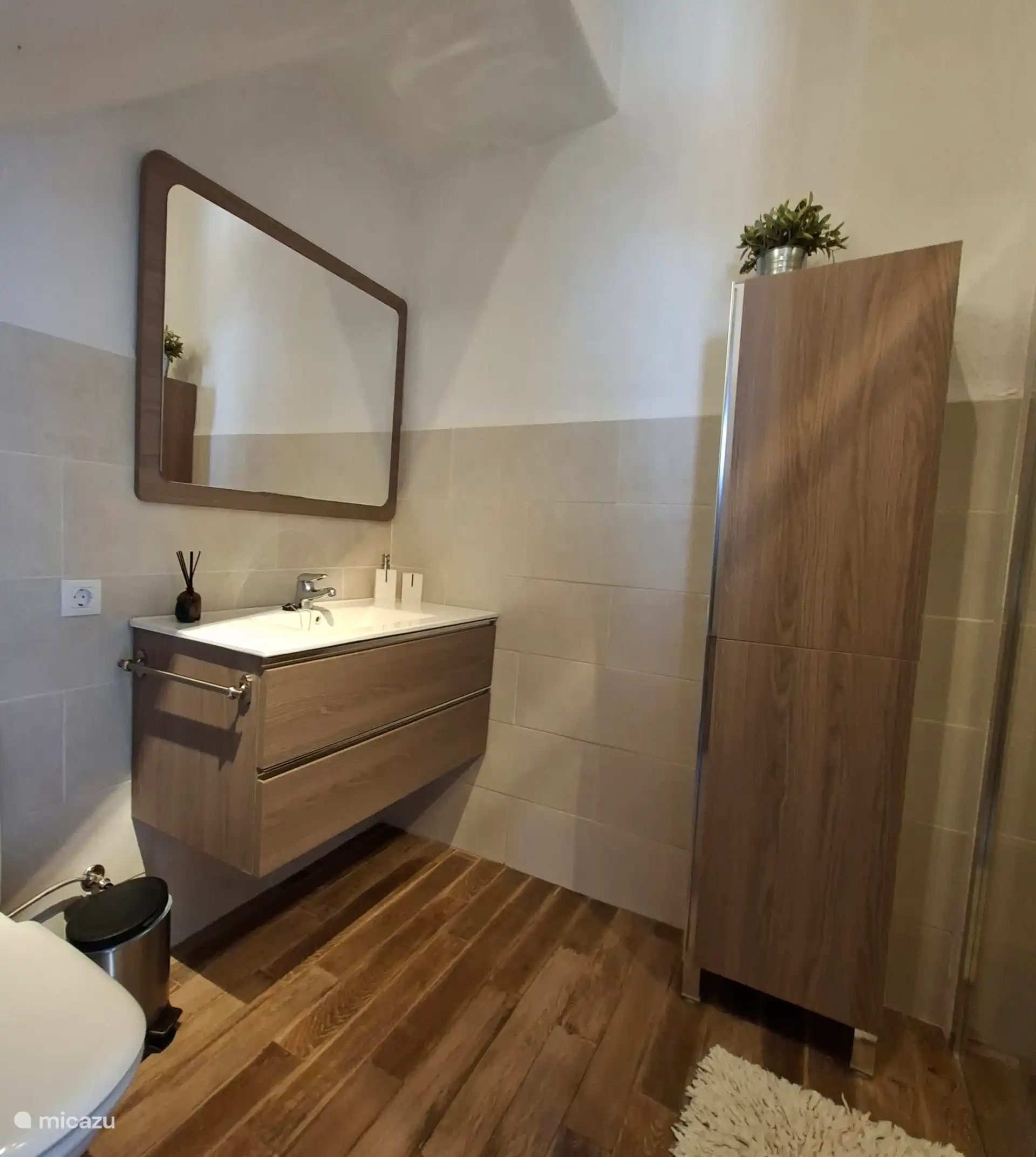 Moderne grote badkamer met wastafel, handdoekenkas, toilet en douche.