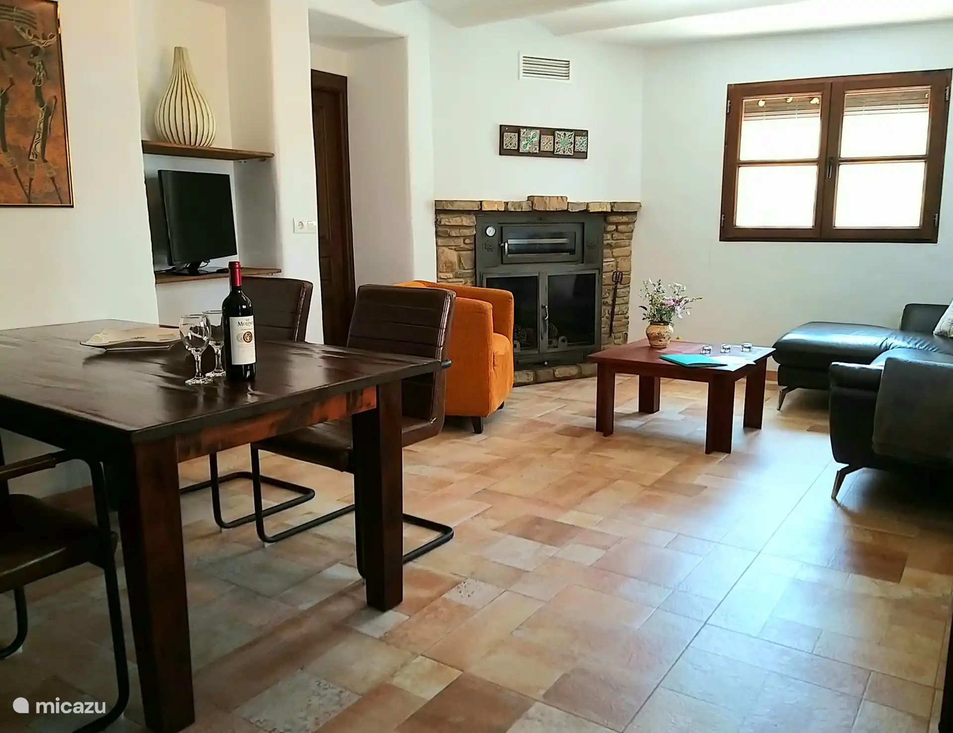 Open woonkamer met 5 zits hoekbank, stoel en eettafel met 6 stoelen.