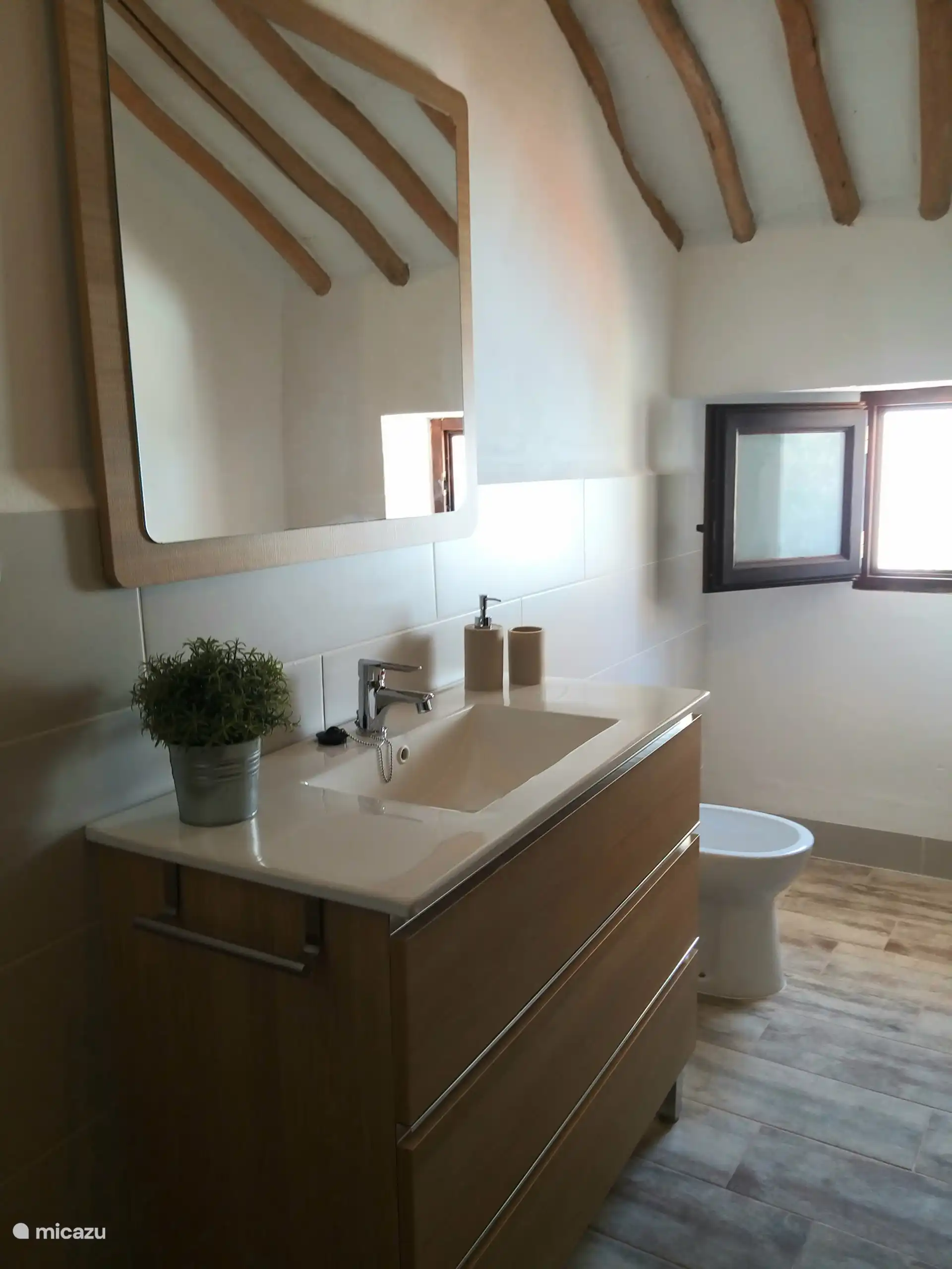 En suite moderne grote badkamer met wastafel, bidet, toilet en grote douche.