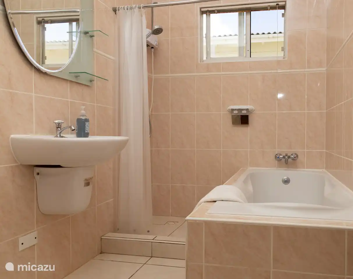 Das Badezimmer im Obergeschoss mit Badewanne und Warmwasserdusche.