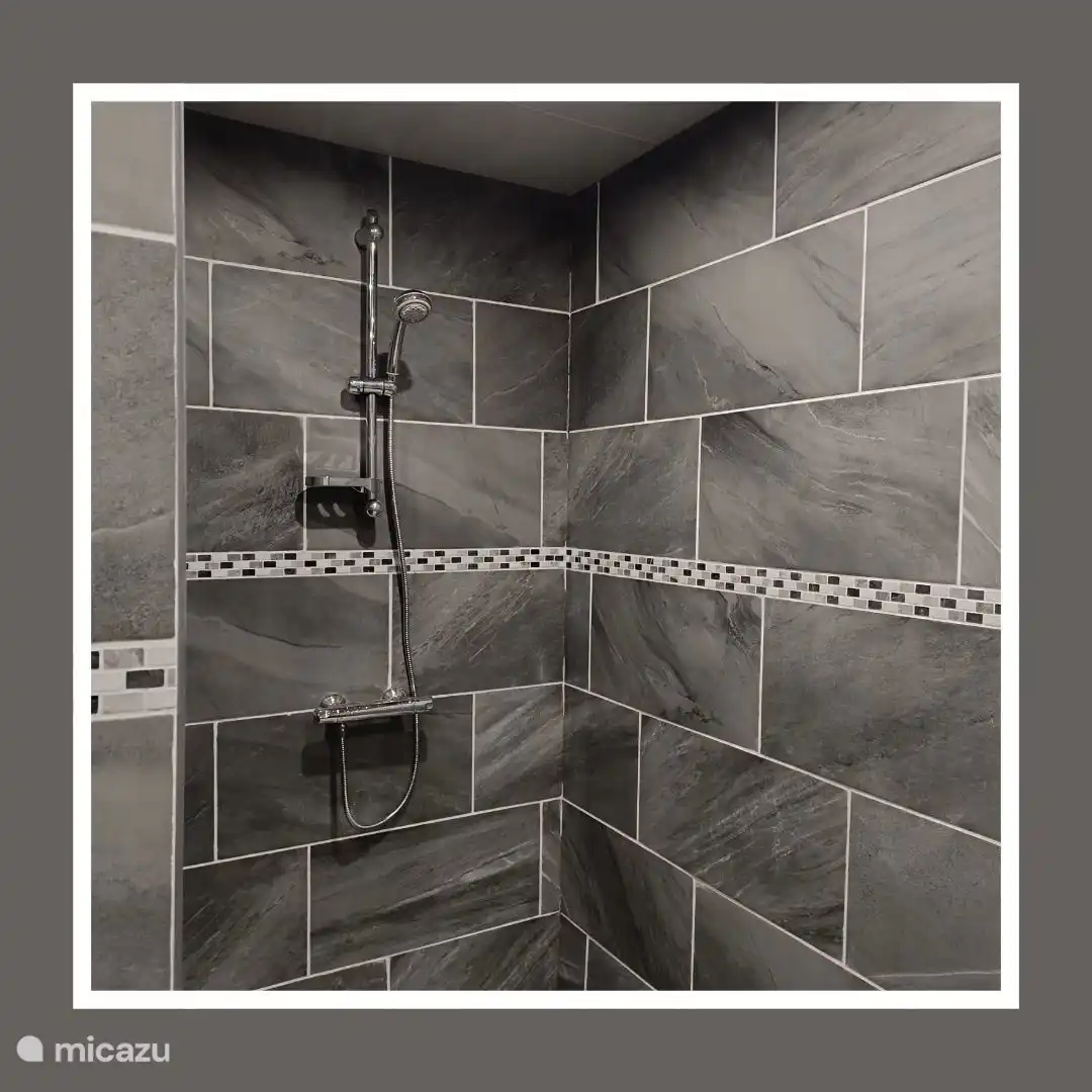 Es gibt ein geräumiges Badezimmer mit ebenerdiger Dusche, WC und Doppelwaschbecken.