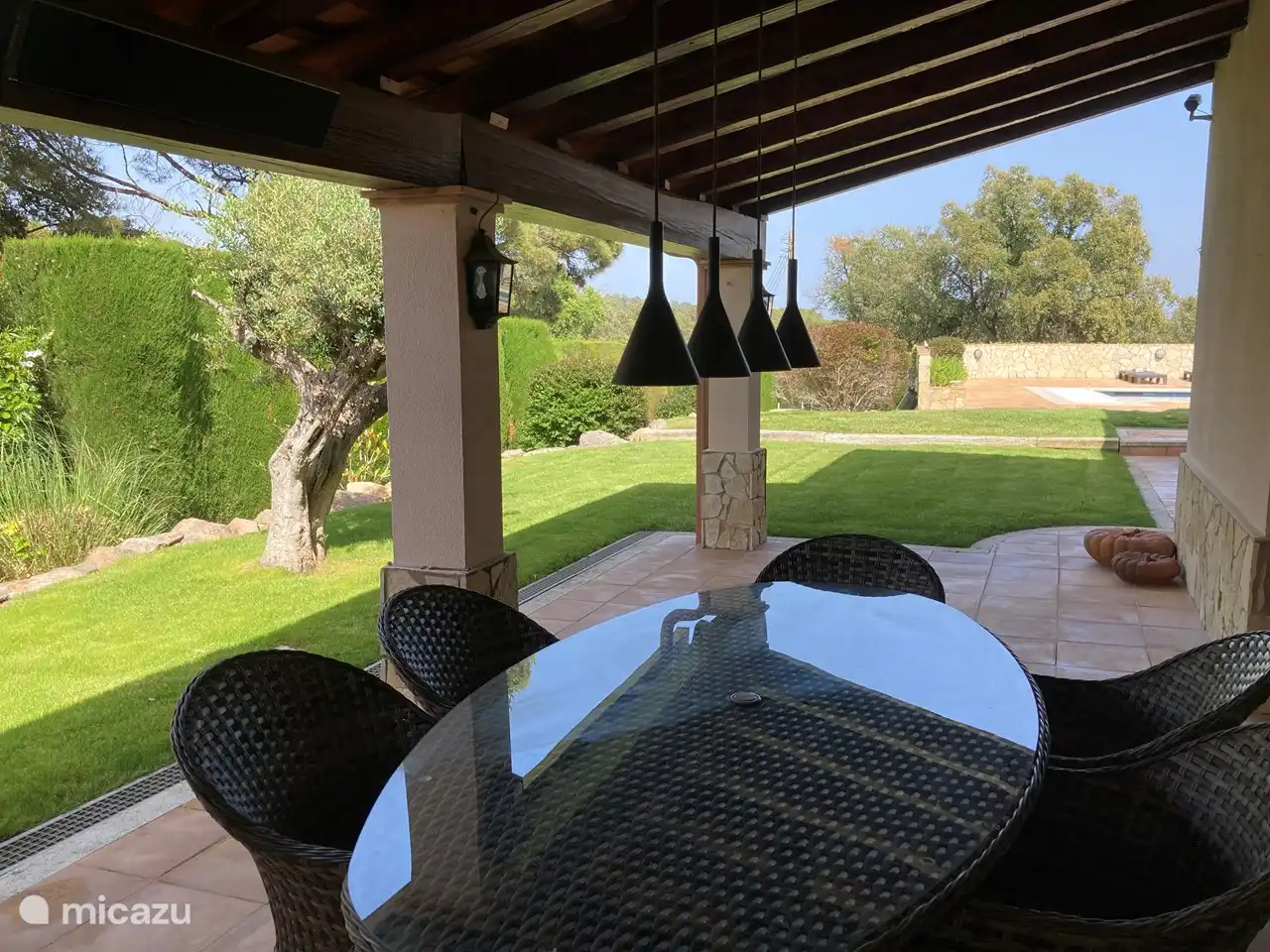 Überdachte Terrasse mit großem Tisch und bequemen Stühlen zum Essen im Freien