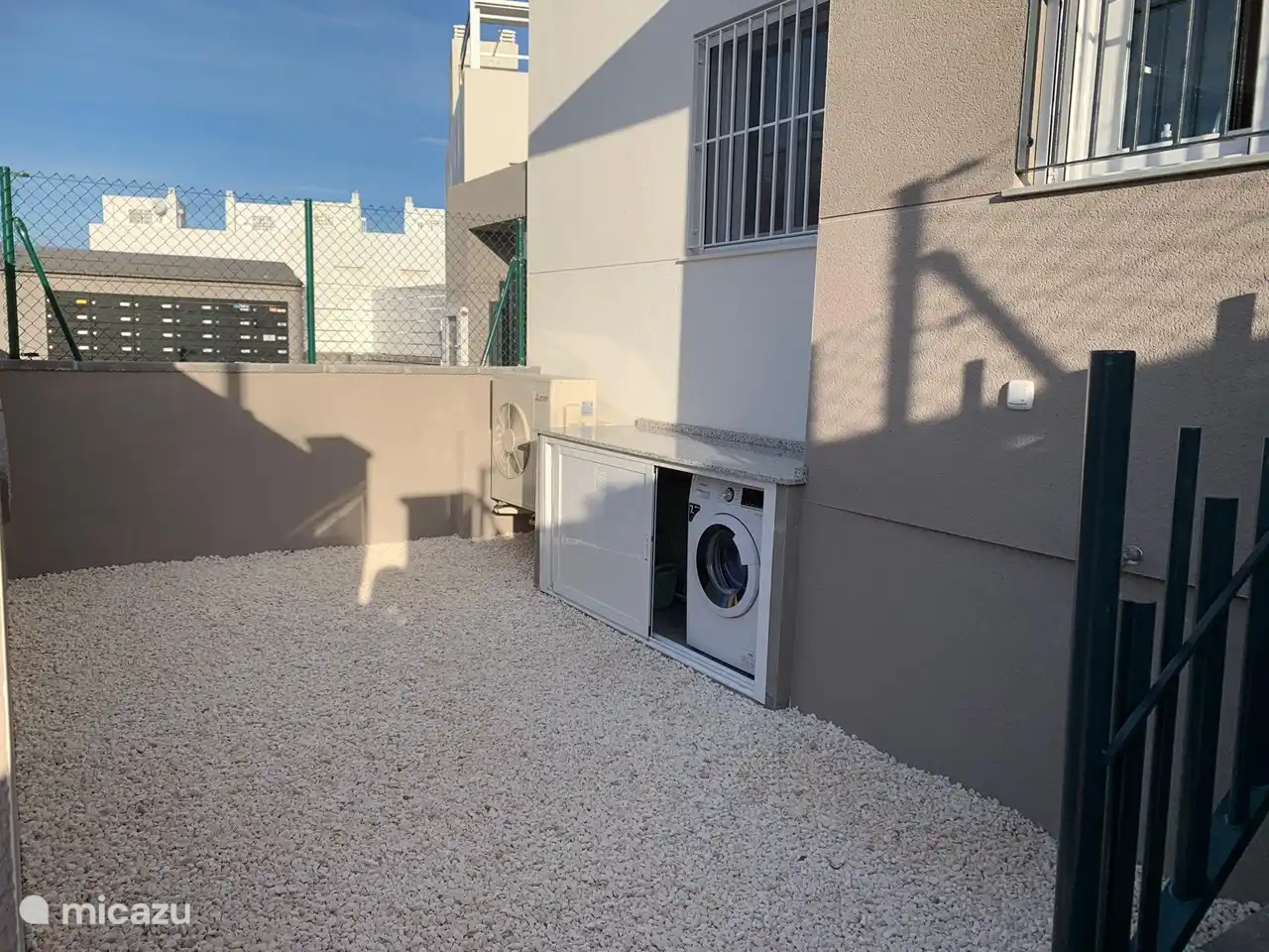 Die Waschmaschine ist bequem in einem geschlossenen Raum auf der Terrasse vor der Wohnung verborgen