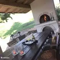 Le portique à côté de la maison, côté cuisine. Une belle longue table avec barbecue