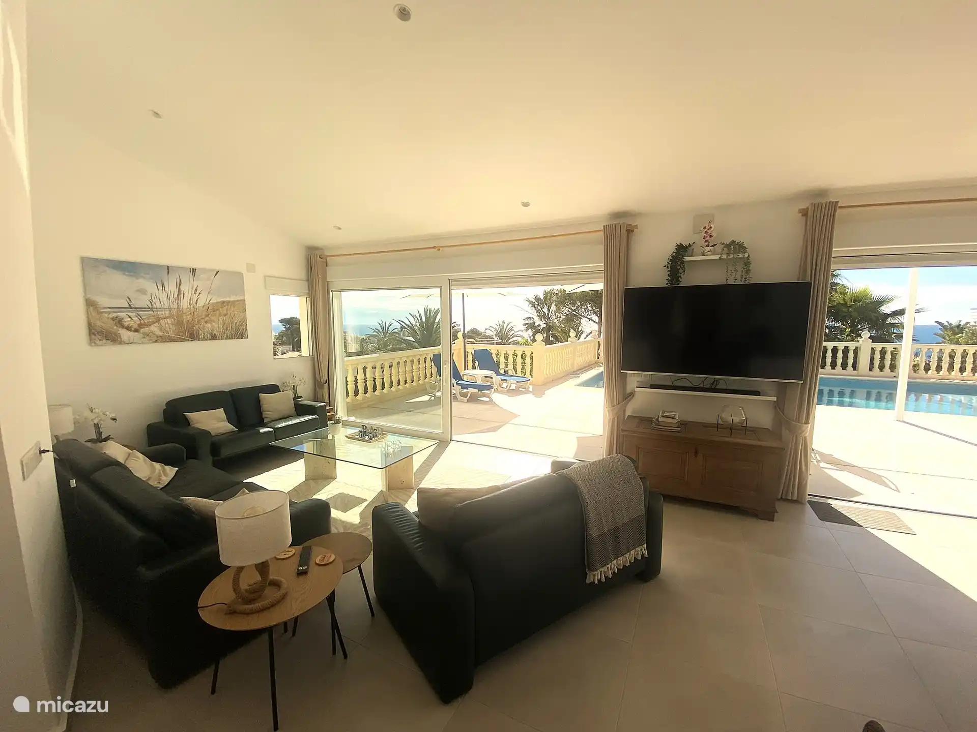 Geräumige Sitzecke mit 3 bequemen Sofas und einem 65-Zoll-Smart-TV mit Chromecast, Netflix und Soundbar. Geräumige Schiebetüren mit Blick auf die Terrasse, den Pool und das Meer.