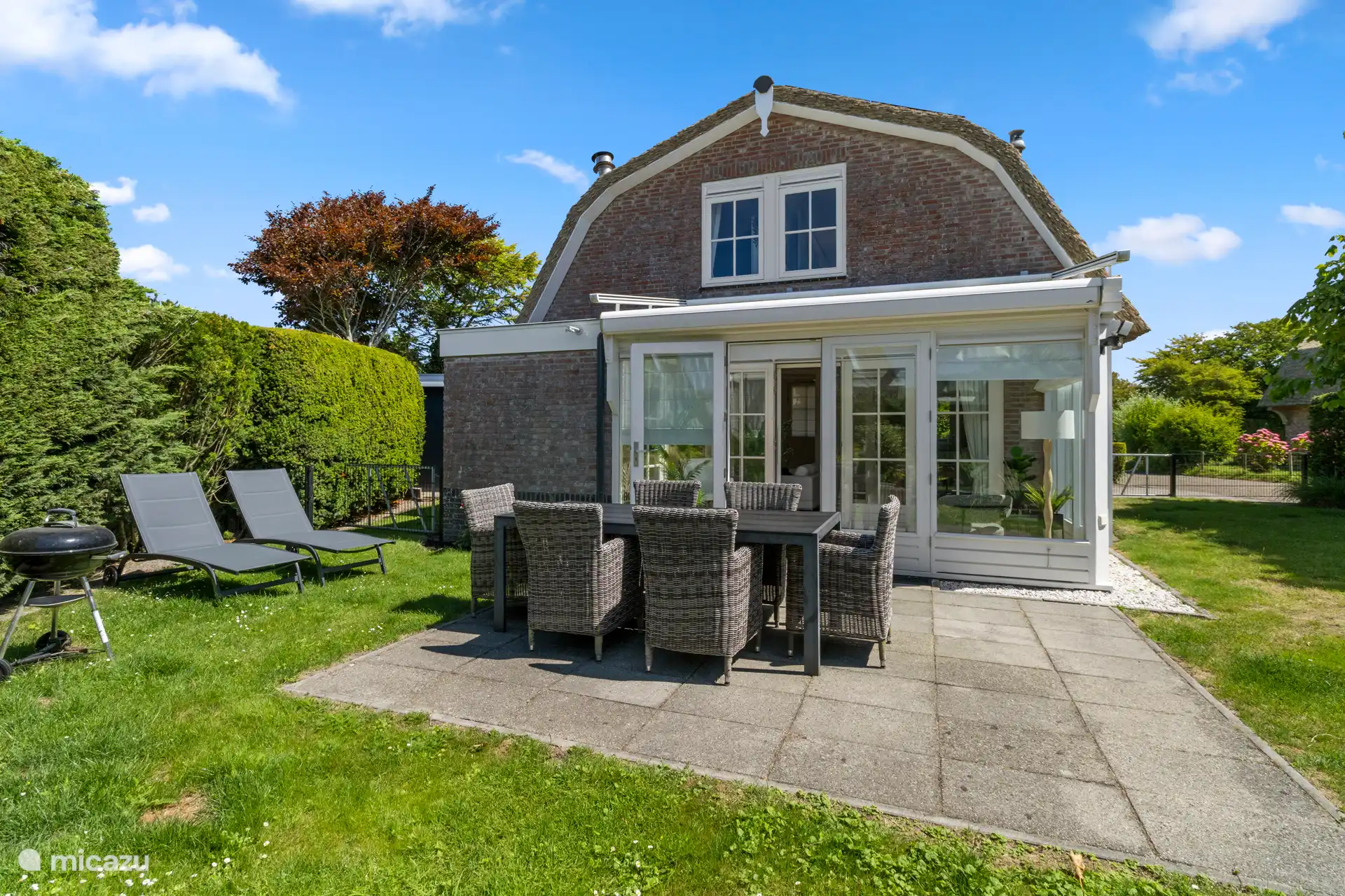 Terrasse mit Gartentisch, Sonnenliegen und Grill.