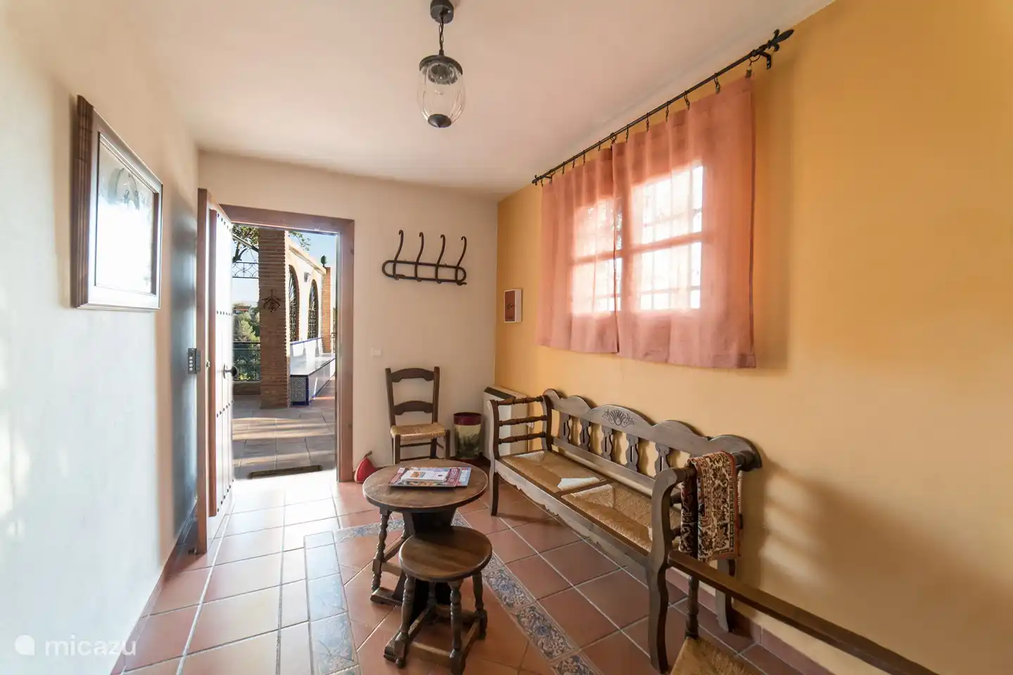 the hall below with couch / seat and coat rack.