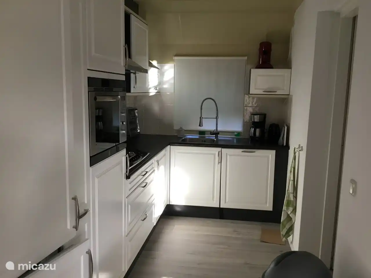 Ein weiteres Foto der Küche. Die Tür rechts bietet Zugang zum Hauswirtschaftsraum. Es gibt unter anderem eine Waschmaschine. Außerdem gibt es Platz für Fahrräder.