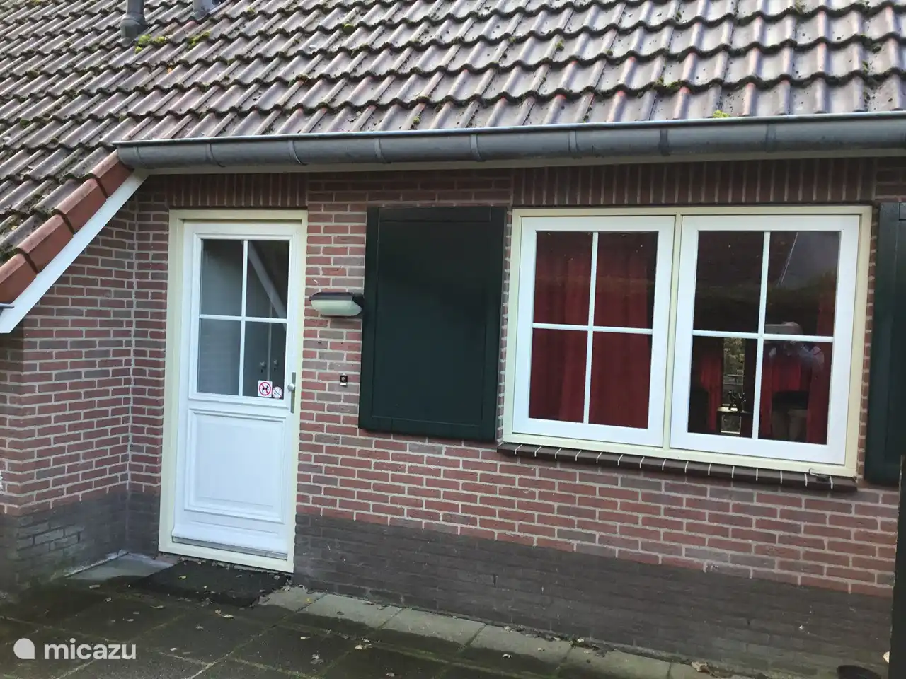 Auf dieser Seite des Ferienhauses sehen Sie die Haustür mit dem Seitenfenster des Wohnzimmers.