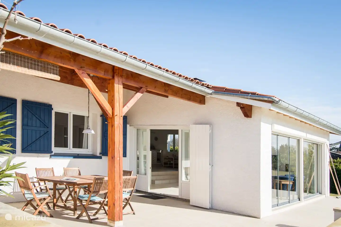 Blick vom Garten auf überdachte Terrasse (noch mit dem alten Tisch) und Wohnzimmer