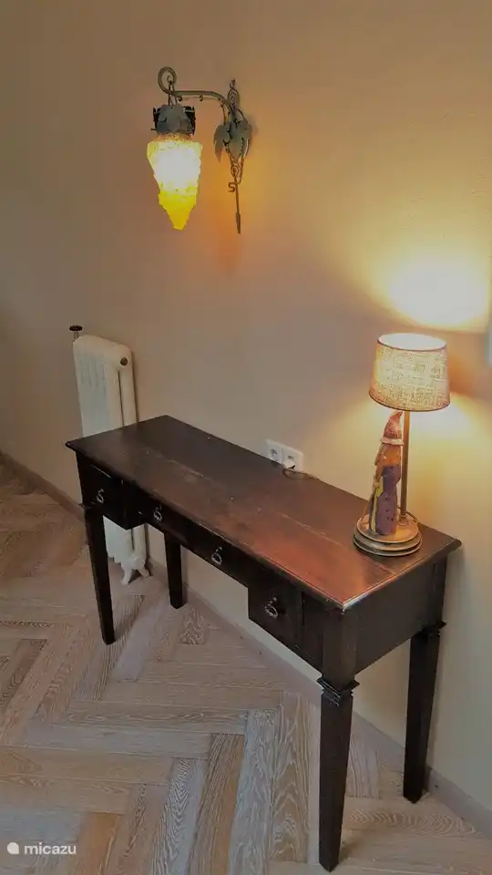 Im Schlafzimmer ein nostalgischer Beistelltisch mit einer speziellen Lampe eines Freundes, auf der ein Holzgnom ('Holzschnitzerei') steht.