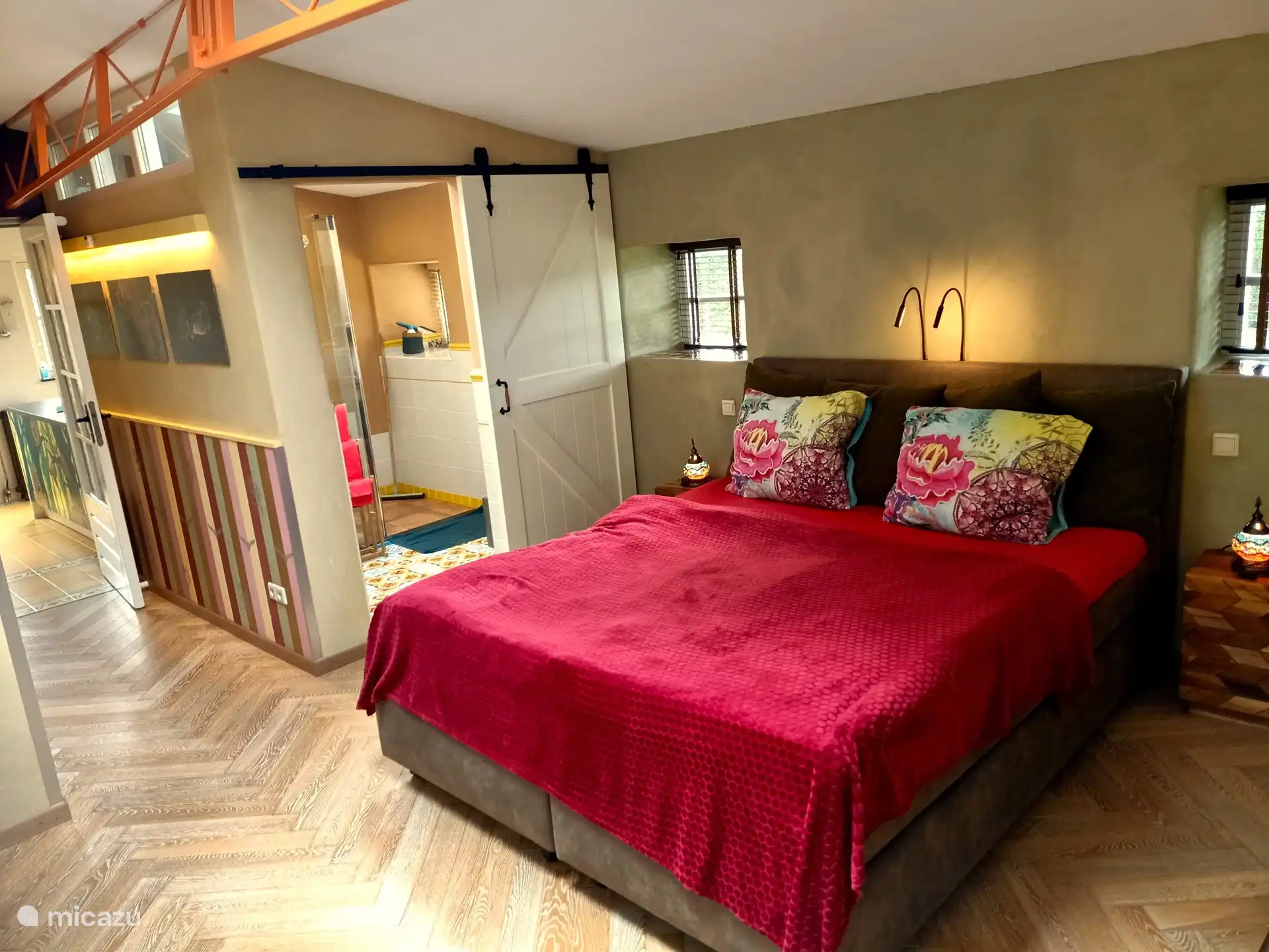 Ein geräumiges Schlafzimmer mit eigenem Bad und Wänden aus Lehmputz. Darin ein schönes Boxspringbett mit den sehr großen Größen von 210 x 180.